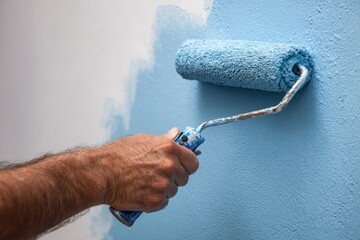 Close-up of hand painting wall with roller