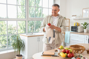 Mature man wiping apple before making cider in kitchen