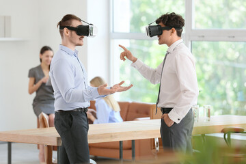 Male business colleagues using VR glasses in office