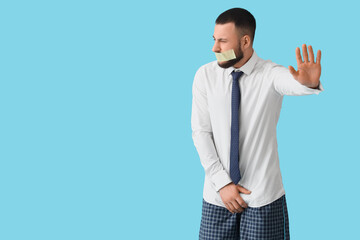 Young businessman in underpants with taped mouth on blue background. Prostate cancer awareness...