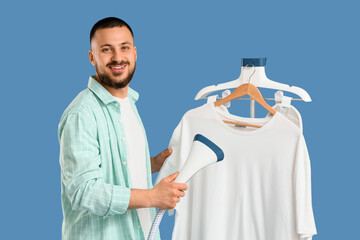 Young man steaming white t-shirt on blue background