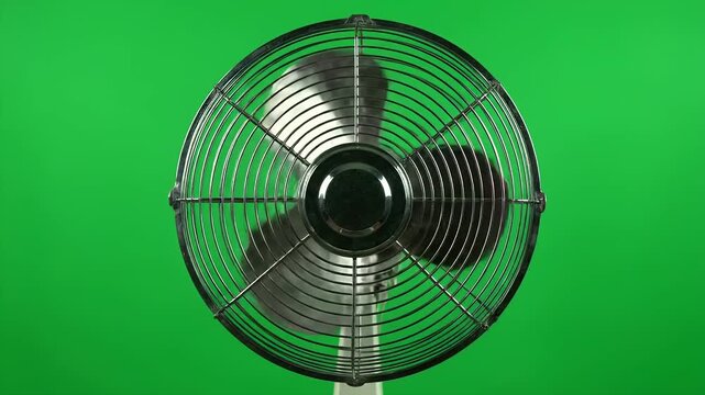 close-up shot of a vintage oscillating fan rotating on a green screen background
