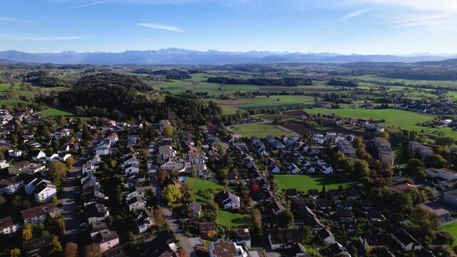 Drone shot of a green town in Switzerland with alps in the background