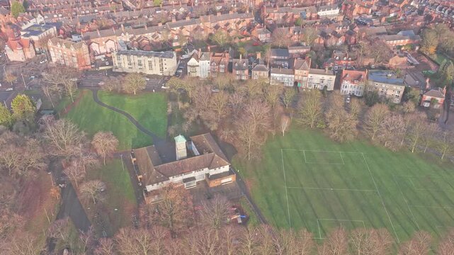 Drone view over Victoria Park in Leicester, Leicestershire, England, showing the central pavilion building with clock tower with rone view over with marked grass sports pitch beside bordering housing.