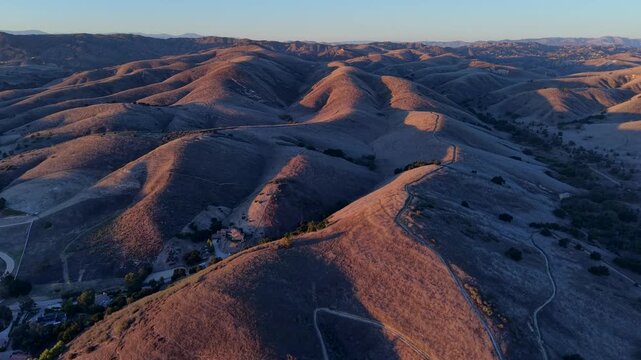 Wide drone view of Cheesboro Trail in Agoura Hills, California, showing expansive rolling hills and winding trails across the Santa Monica Mountains landscape during calm golden hour subset.