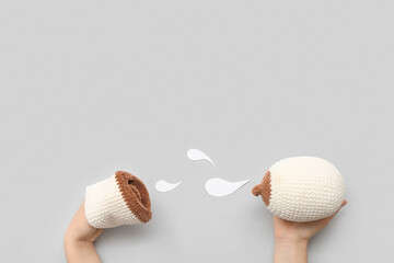 Female hands with knitted model of female breast, human mouth and paper milk drops on grey background. Breast feeding concept
