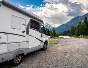 Scenic RV Adventure - Motorhome parked near a lake with mountains and clouds in the background, perfect for travel.
