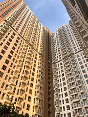 low-angle perspective of two modern high-rise residential apartment buildings.
