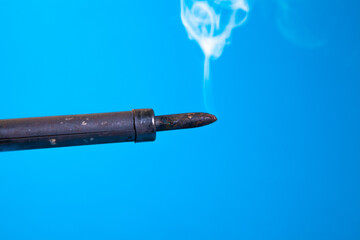 Smoke coming out of a gun tip on a blue background.