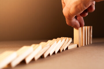 Businessman stopping domino effect from falling. Risk management and strategy concept