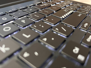 Close-up of a modern backlit laptop keyboard with black chiclet keys.