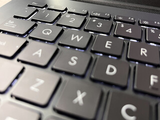 Close-up of a modern backlit laptop keyboard with black chiclet keys.