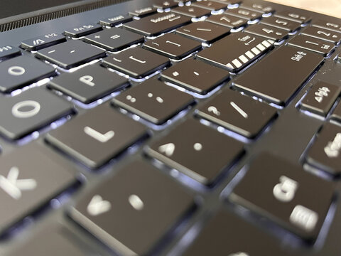 Close-up of a modern backlit laptop keyboard with black chiclet keys.