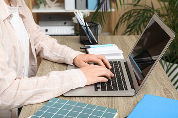 Woman working with modern laptop at table in office, closeup