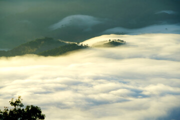 Ethereal Landscape with Fog and Clouds Over Mountainous Terrain