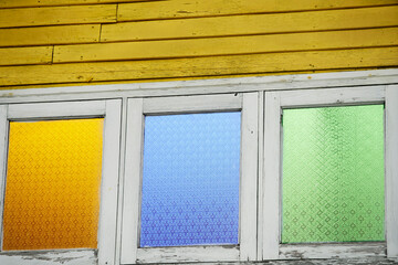 Colorful stained glass windows on weathered wooden wall