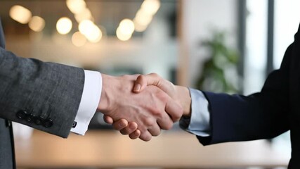 Two professionals engaging in a handshake business agreement in a modern office environment