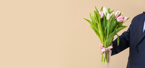 Young man with bouquet of beautiful tulips on beige background with space for text