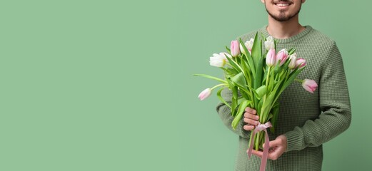 Young man with bouquet of beautiful tulips on green background with space for text