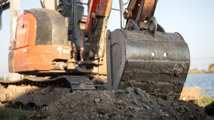 An excavator or backhoe machinery part with soil ground in construction activity. Building industrial scene, close-up and selective focus.