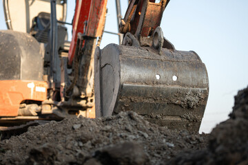 An excavator or backhoe machinery part with soil ground in construction activity. Building...