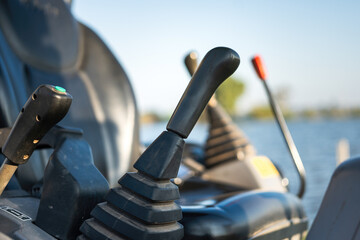 Close-up at backhoe or excavator machine controlling handle at the driver cabin, it using to operate the machine. Industrial equipment object, selective focus.