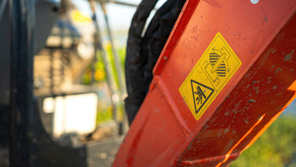 Safety caution sign on the backhoe front part, instruciton for keep out from the swing radius to prevent the accident. Safety sign on the industrial machine, close-up.