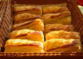 Freshly baked puff pastries arranged in wicker baskets at a bakery display. Golden, flaky layers and warm lighting create an inviting atmosphere, highlighting freshness and quality. Suitable for baker