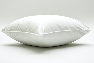 Soft, fluffy white pillow lies on a glossy surface with a neutral background
