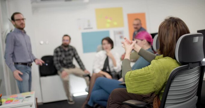 Business team discusses strategies in office setting with mixed group of men and women during afternoon meeting session