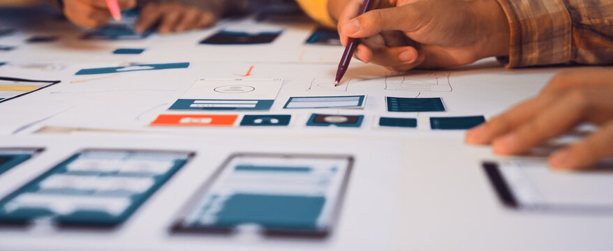 Designers create prototype sketches for a mobile app interface using pens on paper. The collaborative environment stimulates creativity and innovation in the design process. SACTR - Powered by Adobe