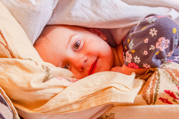 Peaceful baby resting in bed before sleep under soft blanket.