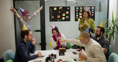 Team celebrates achievement with joy and excitement in office setting with decorations and smiles among business professionals and colleagues