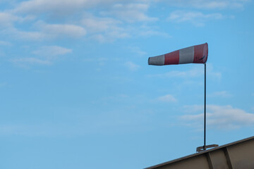 Red and white strip windsock on blue sky background. The equipment using to indication windy speed and direction.
