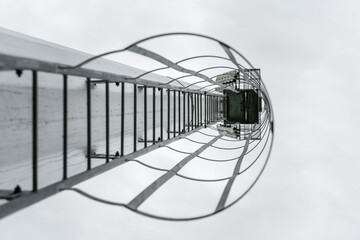 Climbing ladder with falling protection cage of spotlight at sport arena, the way climbing up for maintenance lighting. Close-up with selective focus. © Nattawit