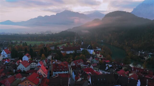 Morning sunrise golden fog Tegelberg Forggensee F&uuml;ssen Fussen birds Allg&auml;u Bavarian Alps Germany Deutschland aerial drone Lech River Bavarian old town buildings autumn fall blue sky forwards motion