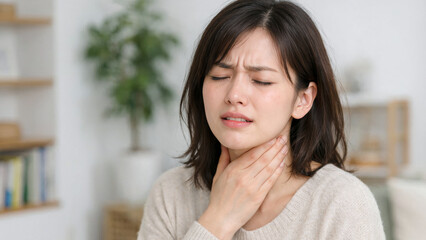 喉の痛みで辛そうな表情を浮かべ、首を手で押さえる若い女性
