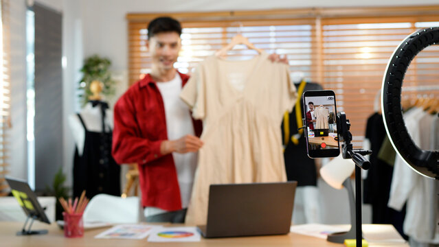 Asian man selling clothes and accessories online by smartphone live streaming, business online e-commerce at home