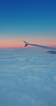 View from the inside airplane window and plane wing, travel with jet flying in the sky above fluffy clouds during sunrise