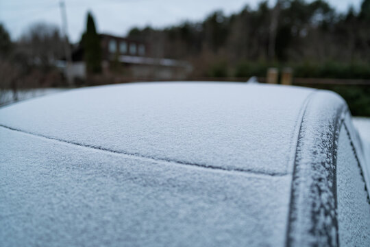 A car covered in a thick layer of frost and ice on a freezing winter morning. Frozen vehicle with white crystallised frost patterns on the surface parked in a residential street during the cold season