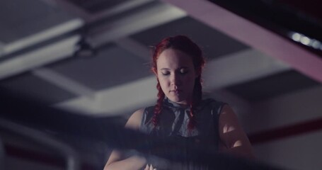 Cropped 4k footage of a female fighter wrapping hand bandages for boxing workout. Focused and steady: female boxer wraps bright green hand wraps, gearing up for rigorous training. Slow motion video. - Powered by Adobe
