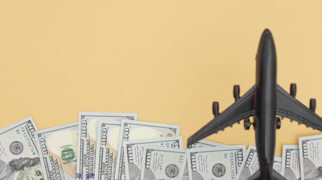 Model airplane gliding over scattered cash bills on a vibrant background, showcasing financial aspirations, camera pans to reveal scene depth