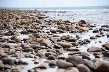 Rocks/stones on the  beach during a daylight on the islands, Thailand.Background image of the beach with sea in the distance with pebble stones.