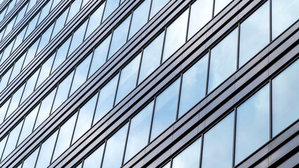 Obraz premium A large building with many windows and a blue sky in the background. The windows are clear and reflect the sky