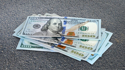 Some amount of nice hundred dollar bills on the asphalt