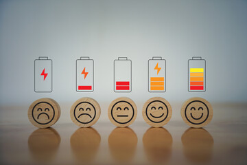 Five wooden blocks with different facial expressions and battery charge levels above them, representing a mood or energy scale. 
