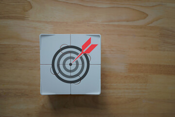 Business strategy and milestone achievement. A winding path leads to a target on a single jigsaw puzzle piece, symbolizing the focus on a key objective as a critical part of a larger plan.