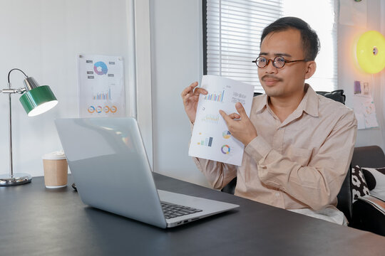 Asia man holding holographic graphs and stock market statistics gain profits. Concept of growth planning and business strategy. Corporate strategy for finance, operations, sales, marketing.