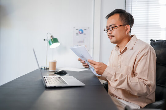 A businessman working on a laptop computer in an office, typing online for his job