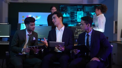 Corporate technology meeting in a modern office. Strategic team analyzing software code and market data displayed on large monitoring screens. Professionals discussing digital transformation and IT so - Powered by Adobe